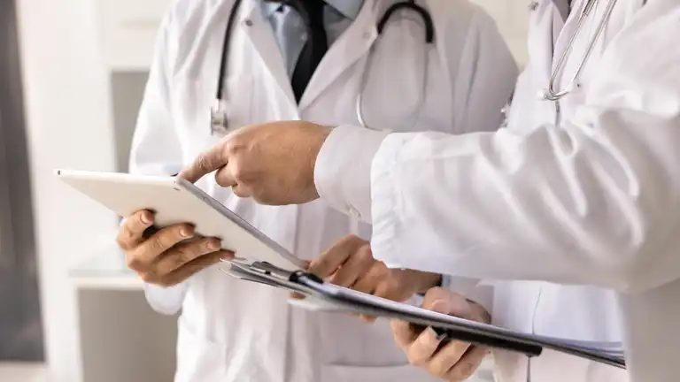 Closeup doctors discussing patient information on electronic tablet on clipboard