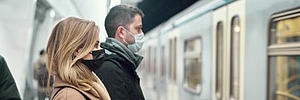 Side view of young man and woman in medical masks standing near carriage in subway