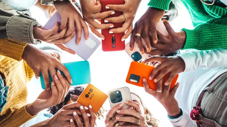 Group of young people using smart mobile phone device outside - Trendy technology concept with guys and girls playing video games app on smartphone - Bright colorful filter